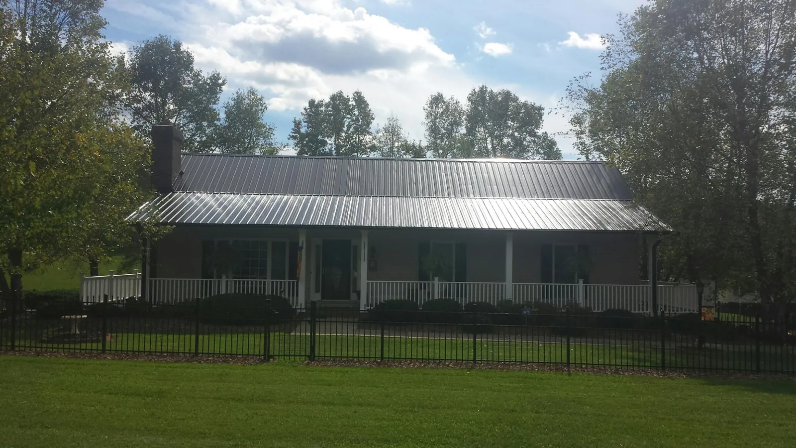 Gray metal roof on a brick ranch with a full width front porch — Gutter Guard Installation work by our crew in Kendrick